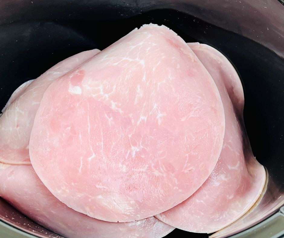 ham slices on top of chicken in the slow cooker